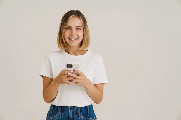 Молода Блондинка Посміхається Під Час Використання Мобільного Телефону Ізольовано Білому — стокове фото