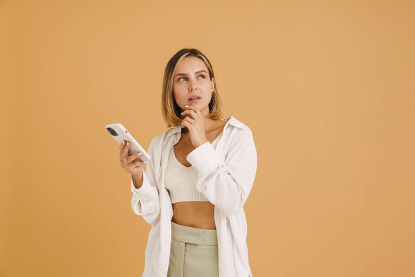 Young Blonde Woman Looking Upward While Using Mobile Phone Isolated Stock Picture