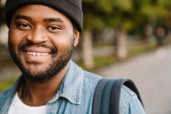 在夏季公园散步时戴着帽子微笑的黑人年轻人 — 图库照片