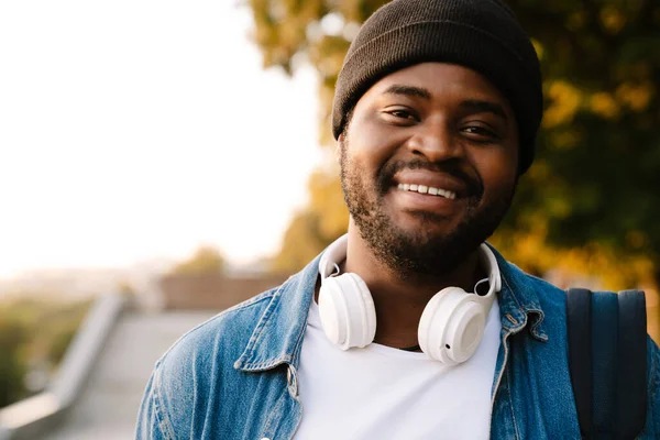 Czarny Młody Człowiek Słuchawkami Uśmiechnięty Podczas Spaceru Parku — Zdjęcie stockowe