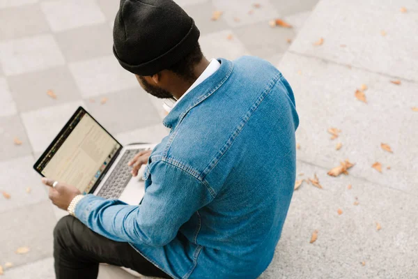Schwarzer Junger Mann Arbeitet Mit Laptop Während Draußen Auf Bank — Stockfoto
