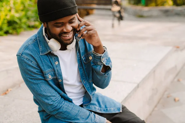 Hombre Negro Con Auriculares Hablando Teléfono Móvil Mientras Está Sentado —  Fotos de Stock