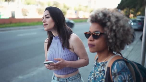 Två Leende Multietniska Kvinnor Pratar Och Anropar Taxi Busstationen Utomhus — Stockvideo