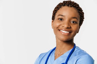 Beyaz arka planda izole edilmiş steteskopla poz verirken gülümseyen siyah doktor.