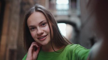 Yeşil tişörtlü, yakışıklı bir kadın sokakta video kaydediyormuş.