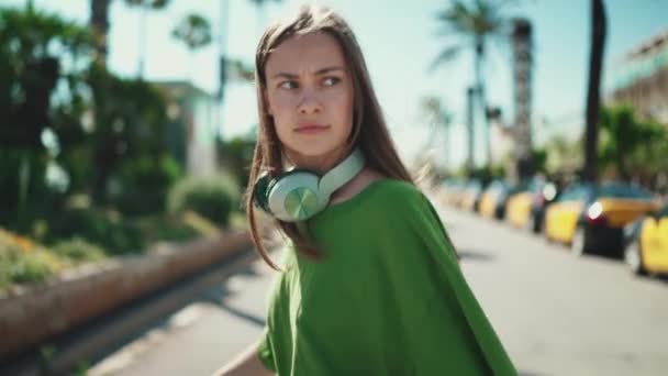 Mujer Rubia Seria Auriculares Con Camiseta Verde Caminando Aire Libre — Vídeos de Stock