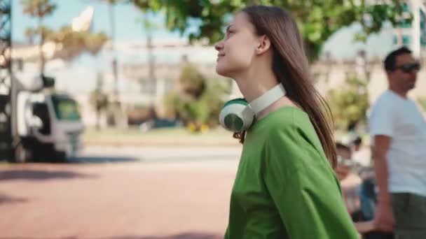 Mujer Rubia Feliz Auriculares Con Camiseta Verde Caminando Ciudad Soleada — Vídeos de Stock