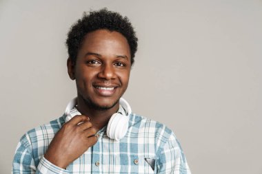 Siyah adam beyaz arka planda izole edilmiş kulaklıklarla poz verirken gülümsüyor.