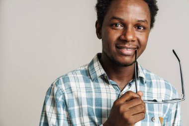 Beyaz arka planda izole edilmiş kameraya gülümseyen gözlüklü genç siyahi adam.