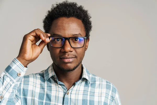 年轻的黑人男子戴着眼镜 摆出一副样子 看着被白色背景隔离的相机 — 图库照片