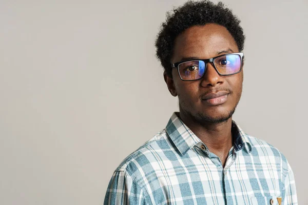 年轻的黑人男子戴着眼镜 摆出一副样子 看着被白色背景隔离的相机 — 图库照片