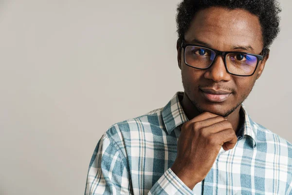 Siyah gözlüklü genç adam beyaz arka planda yalnız poz veriyor ve kameraya bakıyor.