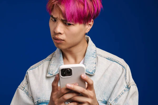Asiatischer Junge Jeansjacke Runzelt Die Stirn Während Sein Handy Isoliert — Stockfoto