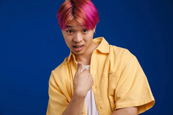 亚洲男孩震惊了 一头粉色的头发在蓝色的背景下对着自己摆弄手指 — 图库照片