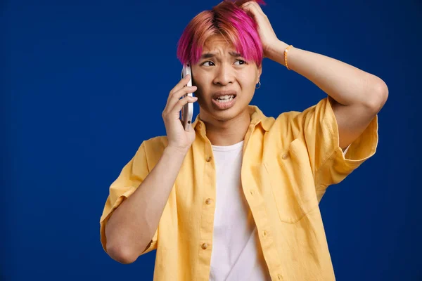 분홍색 머리를 휴대폰으로 얘기하는 아시아 소년은 배경에 고립되어 있었다 — 스톡 사진