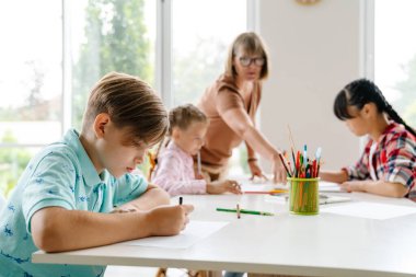 Sanat okulunda ders sırasında öğrencileriyle konuşan olgun bir öğretmen.
