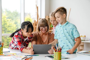 Sanat okulunda ders sırasında tablet bilgisayar kullanan yetişkin öğretmenler ve öğrenciler.
