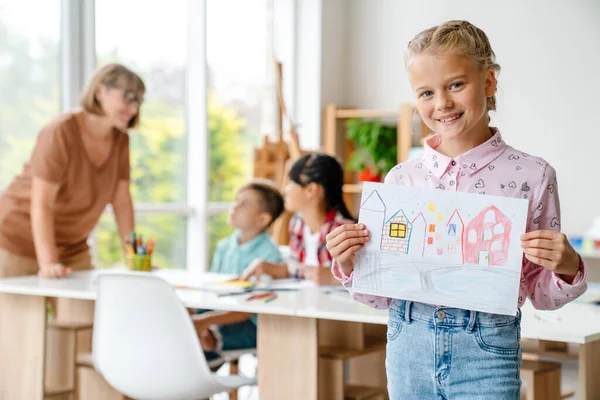 Menina Loira Branca Sorrindo Mostrando Seu Desenho Durante Aula Escola — Fotografia de Stock