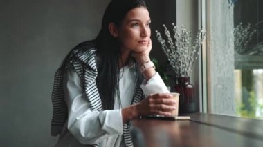 Güzel esmer kadın, kafede otururken akıllı bakışlara ve telefonla mesajlaşmalara bakıyor.