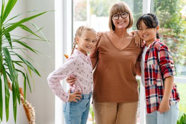 Beyaz olgun öğretmen öğrencilerini kucaklarken gülümsüyor.