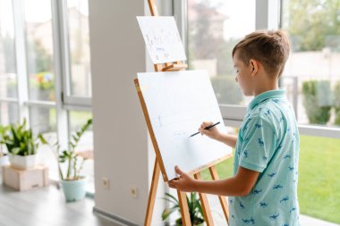 Sanat okulunda resim çizen beyaz sarışın çocuk.