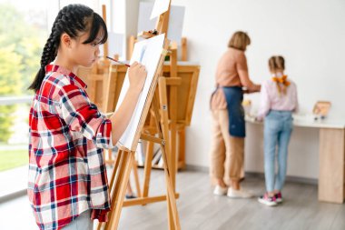 Sanat okulunda kapalı alanda resim çizen Asyalı kız.