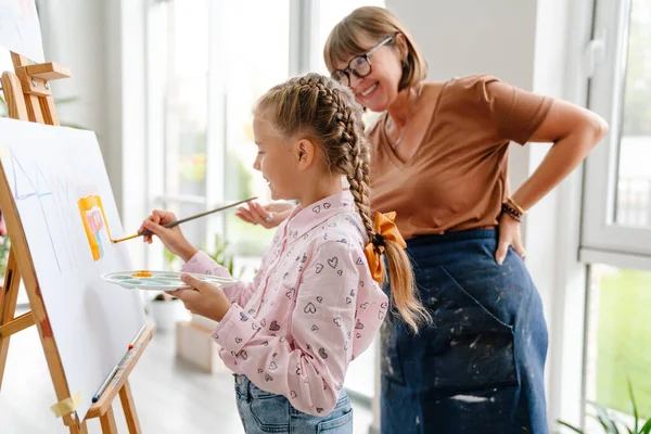 Sanat okulunda sınıf boyunca öğrencileriyle konuşan beyaz bir öğretmen.