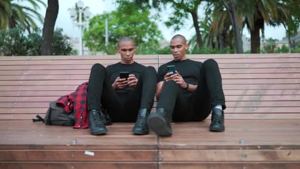 Two Confident Bald African Brothers Talking Typing Phone While Sitting — Stock Video