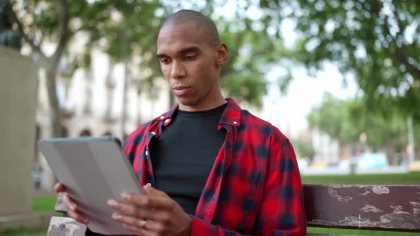 Grave Calvo Africano Hombre Escribiendo Tableta Digital Banco Aire Libre — Vídeo de stock