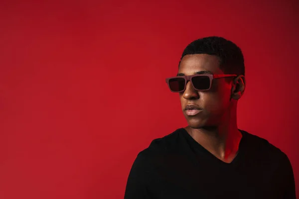 Young Black Man Wearing Sunglasses Posing Looking Aside Isolated Red — Stockfoto
