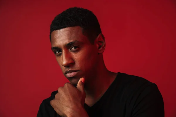 Joven Hombre Negro Sosteniendo Barbilla Mirando Cámara Aislada Sobre Pared —  Fotos de Stock