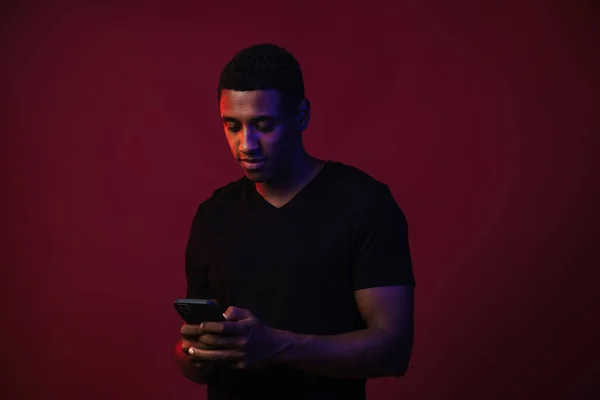 Young Black Man Shirt Using Mobile Phone Isolated Red Wall — Stockfoto