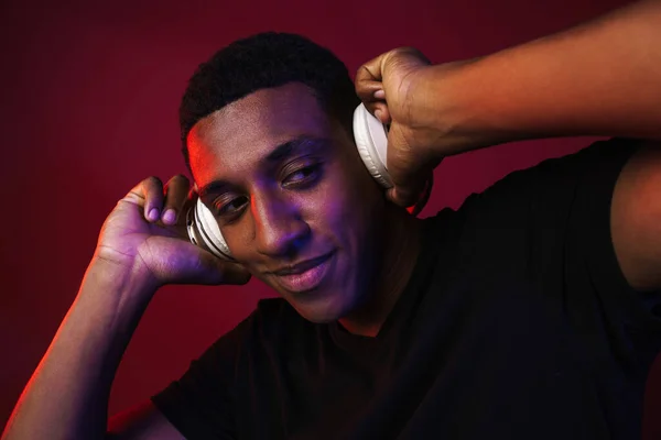 Joven Hombre Negro Sonriendo Mientras Escucha Música Con Auriculares Aislados —  Fotos de Stock