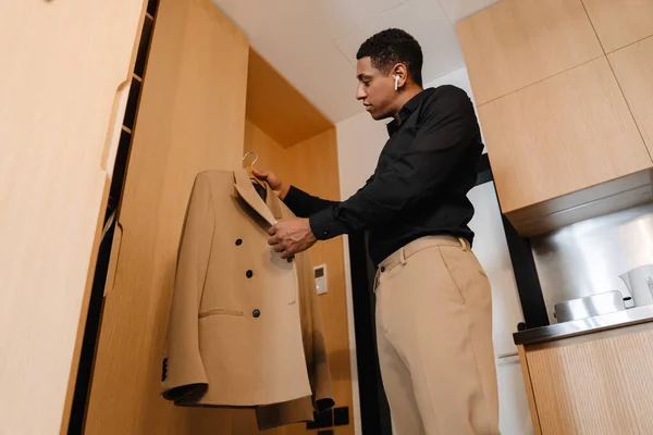 Black Man Listening Music Earphones Holding His Jacket Hotel — Stock Photo, Image