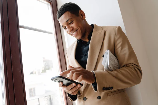 Black Man Wearing Suit Using Cellphone While Standing Window Indoors — Stock Photo, Image