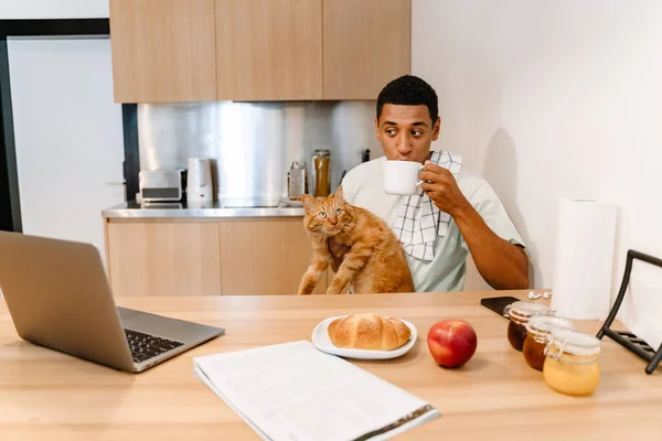 Black man holding his cat while having breakfast in hotel