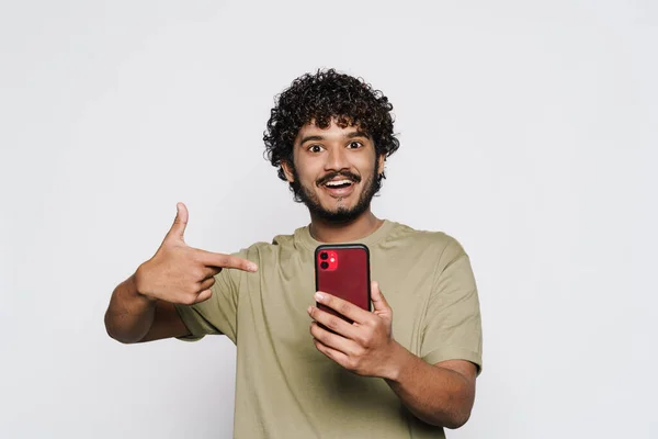 Ung Skäggig Man Håller Och Pekar Finger Sin Mobiltelefon Isolerad — Stockfoto