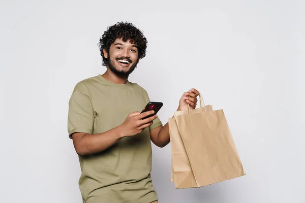 Young Middle Eastern Man Shopping Bags Using Cellphone Isolated White — Stock Photo, Image