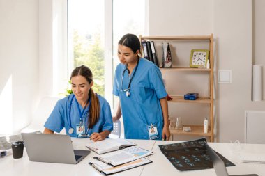 Ofiste dizüstü bilgisayarlarla çalışan çok ırklı kadın doktorlar.