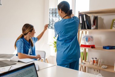 Ofiste çalışırken röntgen çeken çok ırklı kadın doktorlar.