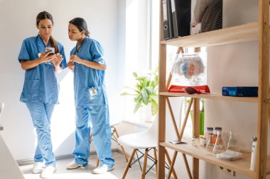 Ofiste çalışırken konuşan ve cep telefonu kullanan çok ırklı kadın doktorlar.