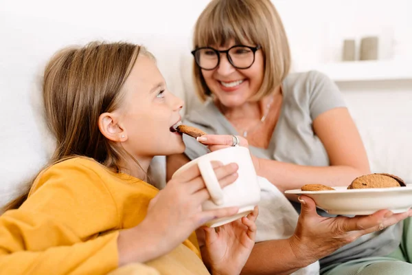 White Girl Drinking Tea Eating Cookie Her Grandmother While Sitting — Stockfoto
