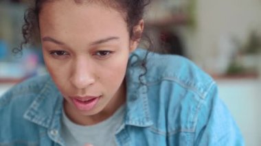 Kahkahalar atan afro saçlı bir kadın laptopta çalışırken kafede oturuyor.