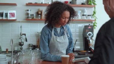 Smiling woman barista talking with customer in cafe