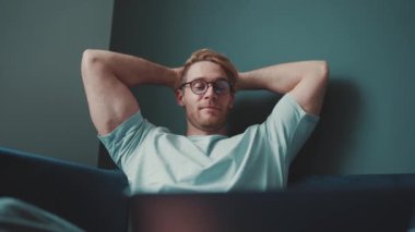 Gözlüklü, elleri havada dizüstü bilgisayara bakan pozitif sarışın atletik bir adam.