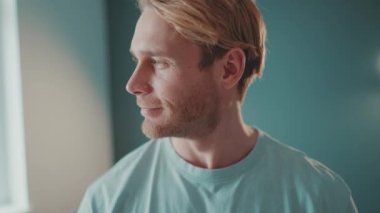 Yakışıklı sarışın atletik adam yan tarafa bakıyor ve evde kameraya bakıyor.
