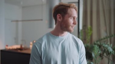 Pretty blond athletic man looking to the side and at the camera at home