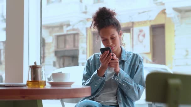 Pretty Woman Afro Hair Typing Phone Drinking Tea While Sitting — Vídeo de Stock