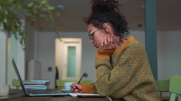 Happy Woman Wearing Yellow Sweater Eyeglasses Writing Something Notepad Laptop — ストック動画