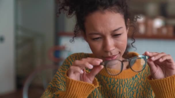 Glimlachende Vrouw Met Gele Trui Veegt Haar Bril Café — Stockvideo